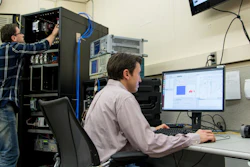 Rick Candell (seated) and Murat Aksu (standing) examine how wireless communications perform in a virtual chemical processing plant created by the NIST Industrial Wireless Test Bed. Data collected from a recent study of wireless propagation in three real factory settings will enhance the ability of the test bed to accurately simulate a variety of industrial environments.