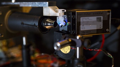 A look at the prototype adaptive PCR device. The small sample in the center is illuminated by an ultraviolet laser on the right and varying levels of fluorescence are detected by the spectrophotometer on the left and are used to control the DNA duplication process.