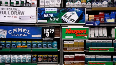 In this Friday, July 17, 2015 file photo, Camel and Newport cigarettes, both Reynolds American brands, are on display at a Smoker Friendly shop in Pittsburgh. British American Tobacco Plc has agreed to fully take over Reynolds American Inc. on terms that are improved from an initial bid made last year.