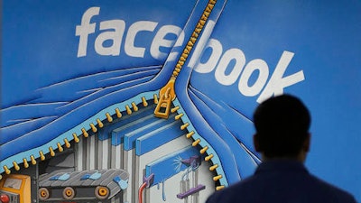 In this Friday, March 15, 2013, file photo, a Facebook employee walks past a sign at Facebook headquarters in Menlo Park, Calif. Despite loudly touted efforts, the tech industry is making very little progress in diversifying its workforce, especially in technical and leadership positions. In 2014, 2 percent of Googlers were black and 3 percent were Hispanic, numbers that haven’t changed since. The picture is similar at Facebook and Twitter.