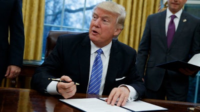 In this Monday, Jan. 23, 2017, file photo, President Donald Trump signs an executive order to withdraw the U.S. from the 12-nation Trans-Pacific Partnership trade pact agreed to under the Obama administration in the Oval Office of the White House in Washington.