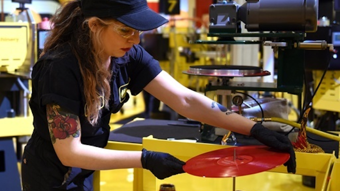 Alejandra Billegas, of Detroit, presses The White Strips 'De Stijl' album during Third Man Records Cass Corridor grand opening of the pressing plant to the public, Saturday, Feb. 25, 2017 in Detroit. Detroit-raised rocker Jack White is building on a vision to blend music and manufacturing in a part of his hometown that long inspired him. The Grammy-winning singer, songwriter, guitarist, drummer and producer is overseeing the launch of a vinyl record pressing plant in the back of his Third Man Records shop north of downtown Detroit.