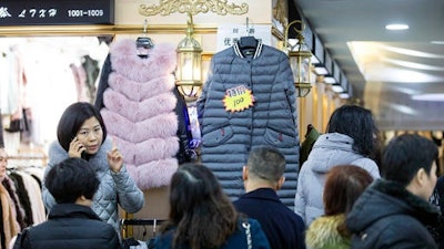 In this Jan. 12, 2017 photo, shoppers inspect clothing at a wholesale clothing market in Hangzhou in eastern China's Zhejiang province. China reports that its exports rose 7.9 percent in January, rebounding from the previous month's contraction, while imports gained 16.7 percent.