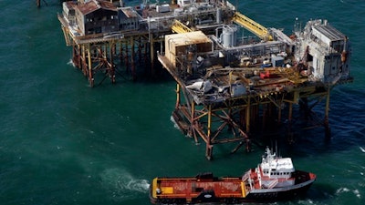 In this Friday, Nov. 16, 2012, file aerial photo, a supply vessel moves near Black Elk Energy's oil platform damaged by an explosion and fire in the Gulf of Mexico about 17 miles from Grand Isle, La. An oil industry services company will pay $9.5 million in penalties for Gulf of Mexico safety violations and for pollution from the 2012 offshore platform fire that killed three workers. The penalties against Houston-based Wood Group PSN were announced Thursday, Feb. 23, 2017, by the U.S. Justice Department in Washington and U.S. attorneys in New Orleans and Lafayette, Louisiana, where civil and criminal cases have been playing out.