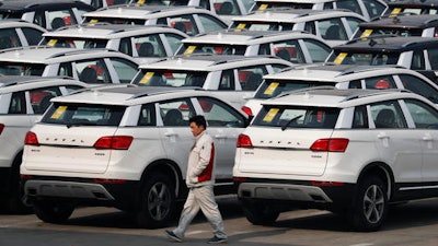 In this Sunday, Feb. 19, 2017 photo, a worker walks past Haval SUV models parked outside the Great Wall Motors assembly plant in Baoding in north China's Hebei province. Great Wall Motors became China’s most profitable automaker by making almost nothing but low-priced SUVs. Now it wants to expand into global markets.