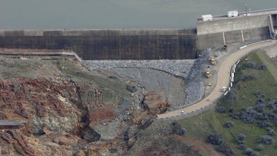 This photo taken Monday, Feb. 13, 2017, shows erosion caused when overflow water cascaded down the emergency spillway, right, of the Oroville Dam in Oroville, Calif. Water flowed over the emergency spillway Sunday morning when Lake Oroville reached capacity, and engineers determined the hillside was eroding faster then expected, undermining the concrete wall. Officials fearing it was about to collapse ordered thousands of residents downstream to evacuate.
