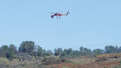 A Skycrane helicopter lowers a load of rocks to fill in a hole on the Oroville Dam's emergency spillway, Tuesday, Feb. 14, 2017, in Oroville, Calif. The barrier, at the nation's tallest dam, is being repaired after authorities ordered mass evacuations for everyone living below the lake out of concerns the spillway could fail and send a 30-foot wall of water roaring downstream.
