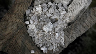 In this Feb. 1, 2017 photo, a handful of snow-melting road salt mined by the American Rock Salt Co. is photographed at a service station in Williamsville, N.Y.