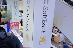 In this Nov. 7, 2016, file photo, a shopper standing on an escalator passes by the company logo of SoftBank at an electronic shop in Tokyo. The $3.3 billion acquisition by SoftBank Group Corp., the Japanese telecommunications, internet and solar energy giant, of Fortress Investment Group marks tycoon Masayoshi Son’s latest step in building a technology investment empire.