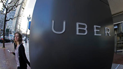 In this file photo taken Tuesday, Dec. 16, 2014, a woman walks past the company logo of the internet car service, Uber, in San Francisco, USA. Uber’s chief executive ordered an urgent investigation Monday Feb. 20, 2017, into a sexual harassment claim made by a female engineer who alleged her prospects at the company evaporated after she complained about advances from her boss.