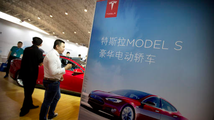 In this April 25, 2016, file photo, visitors look at a Tesla Model S electric car on display at the Beijing International Automotive Exhibition in Beijing. Tesla said August 15, 2016, that the removal of the term autopilot from its website for China was a mistake and the term is being restored.