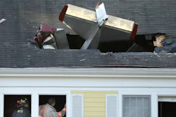 Firefighters investigate the scene after a single-engine aircraft crashed into a building across the Merrimack River from Lawrence Municipal Airport, Tuesday, Feb. 28, 2017, in Methuen, Mass. According to police, the pilot of the home-built plane was killed, while no one in the building was hurt.