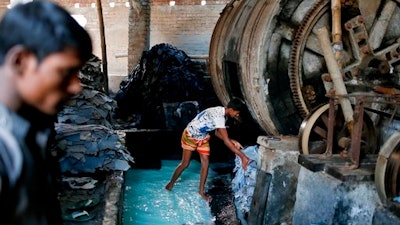 In this Monday, Feb. 6, 2017 photo, a Bangladeshi boy processes animal hide inside a factory at the highly polluted Hazaribagh tannery area in Dhaka, Bangladesh. Hazardous, heavily polluting tanneries with workers as young as 14 supplied leather to companies that make shoes and handbags for Western brands, a nonprofit group that investigates supply chains says.