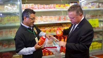 Brazil's Agriculture Minister Blairo Maggi, right, accompanied by a sanitary inspection agent, collect meat products for testing, in a supermarket in Brasilia, Brazil, Wednesday, March 22, 2017. South Africa is partially suspending imports of Brazilian meat, the latest country to do so in the wake of an inspection scandal. Brazilian investigators charge that health inspectors in the South American country were bribed to overlook the sale of expired meats and chemicals and other products were added to meat to improve its appearance and smell.