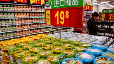 In this Tuesday, March 14, 2017 photo, a man looks at imported wines on display for sale near the imported cookies and nuts, at Walmart in Beijing. China's trading partners are bringing the top U.N. food standards official to Beijing in a last-ditch attempt to persuade regulators to scale back plans for intensive inspections of food imports - including such low-risk items as wine and chocolate - that Washington and Europe say could disrupt billions of dollars in trade.