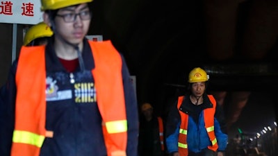 Workers walk out from a tunnel leading to a construction site of the Badaling Great Wall Station in between of Beijing-Zhangjiakou high-speed railway, in Beijing, Wednesday, March 1, 2017. China's labor minister says Beijing will cut another 500,000 jobs this year from steel, coal and other heavy industries to reduce excess production capacity that is flooding markets and depressing global prices.
