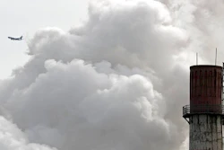 In this Feb. 28, 2017 file photo, a passenger airliner flies past steam and white smoke emitted from a coal-fired power plant in Beijing. Led by cutbacks in China and India, construction of new coal-fired power plants is falling worldwide, improving chances climate goals can be met despite earlier pessimism, three environmental groups said Wednesday, March 22, 2017.