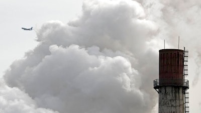 In this Feb. 28, 2017 file photo, a passenger airliner flies past steam and white smoke emitted from a coal-fired power plant in Beijing. Led by cutbacks in China and India, construction of new coal-fired power plants is falling worldwide, improving chances climate goals can be met despite earlier pessimism, three environmental groups said Wednesday, March 22, 2017.