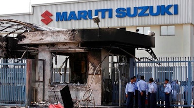 In this Thursday, July 19, 2012, file photo, security guards stand near a burnt down reception block of Maruti Suzuki factory in Manesar, near New Delhi, India. A court in north India convicted 31 factory workers Friday for taking part in violence at a factory run by the country's largest automobile manufacturer Maruti Suzuki that led to the death of a manager, news reports said.