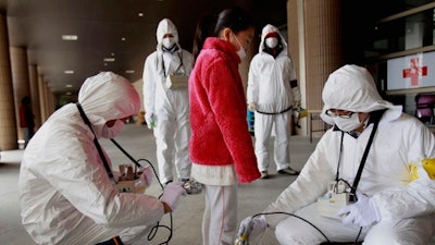 In this March 24, 2011 file photo, a young evacuee is screened at a shelter for leaked radiation from the tsunami-ravaged Fukushima Dai-ichi nuclear power plant in Fukushima, northeast of Tokyo. Doctors say over 180 thyroid cancer cases among Fukushima youngsters found since the nuclear accident cannot be linked to radiation, which they say is not the region’s biggest cause of health problems.