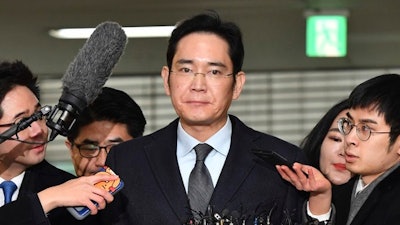In this Feb. 13, 2017 file photo, Lee Jae-yong, center, vice chairman of Samsung Electronics, arrives to be questioned as a suspect in a corruption scandal at the office of the independent counsel in Seoul. Lee, the billionaire Samsung Group heir, will stand trial on Thursday, March 9 at a Seoul court. He is charged with, among other offenses, offering bribes to President Park Geun-hye and a close friend of hers to strengthen his control over Samsung, the conglomerate founded by his grandfather that is South Korea’s largest and most successful business.