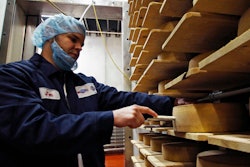 In this Feb. 27, 2017, photo, Jon Conkey cuts a piece from a wheel of Grand Cru Surchoix cheese at the Emmi Roth USA production plant in Monroe, Wis., for labeling. The company won the World Championship Cheese Contest in 2016 for the cheese and since then has seen an increase in sales of the cheese. The contest is organized by the Wisconsin Cheese Makers Association, which also organizes the United States Championship Cheese Contest that runs until March 9 in Green Bay, Wis. The contests are in alternate years.