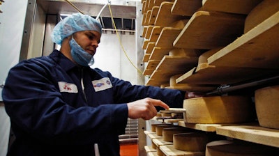 In this Feb. 27, 2017, photo, Jon Conkey cuts a piece from a wheel of Grand Cru Surchoix cheese at the Emmi Roth USA production plant in Monroe, Wis., for labeling. The company won the World Championship Cheese Contest in 2016 for the cheese and since then has seen an increase in sales of the cheese. The contest is organized by the Wisconsin Cheese Makers Association, which also organizes the United States Championship Cheese Contest that runs until March 9 in Green Bay, Wis. The contests are in alternate years.
