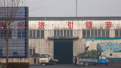In this Dec. 30, 2016, file photo, workers load 'clean coal' promoted by the government at a factory in Qianan, in northern China's Hebei province. China's government said Wednesday, March 29, 2017, it will stick to its promises to curb carbon emissions after President Donald Trump eased U.S. rules on fossil fuel use that were meant to control global warming. A Chinese foreign ministry spokesman said Beijing is committed to the Paris climate agreement.
