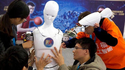 In this Oct. 21, 2016 photo, Chinese students work on the Ares, a humanoid bipedal robot designed by them with funding from a Shanghai investment company, displayed during the World Robot Conference in Beijing.