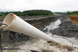 In this Friday June 26, 2015 file photo, a drain pipe sticks out of a coal ash retention pond at the Dominion Power's Possum Point Power Station in Dumfries, Va. The company is moving coal ash from several ponds to one lined pond. As Virginia and its public utilities struggle to cope with the coal ash buried in pits and ponds across the state, tons more of the industrial byproduct is being imported each year.