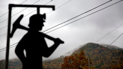 In this Oct. 16, 2014 file photo, fog hovers over a mountaintop as a cutout depicting a coal miner stands at a memorial to local miners killed on the job in Cumberland, Ky.