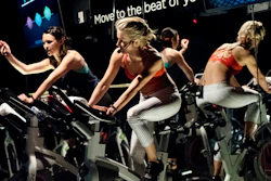 In this March 1, 2017 photo, Jamey Powell, left, and Julianne Hough lead an exercise class as the participants are introduced to the Alta HR fitness tracker at Swerve cycling center in New York. Fitbit is the leading seller of wearable devices, but it’s facing a steep decline because most of its sales are in the U.S., where many people who want a fitness tracker already have one.