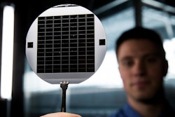 A graduate student at BYU holds up a disc of microchips that have flexible glass membranes.