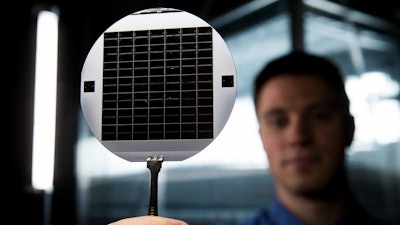 A graduate student at BYU holds up a disc of microchips that have flexible glass membranes.