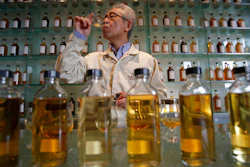 In this March 8, 2017 photo, Suntory's chief blender Shinji Fukuyo demonstrates how he examines the whisky at the Suntory distillery in Yamazaki, near Kyoto, western Japan. 'What’s important for whisky is that its deliciousness must deepen with aging, sitting in the casks for a long time,' said Fukuyo, 55, demonstrating how he examines the whisky in a glass, swirling the crystalline amber spirit against the light.