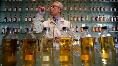 In this March 8, 2017 photo, Suntory's chief blender Shinji Fukuyo demonstrates how he examines the whisky at the Suntory distillery in Yamazaki, near Kyoto, western Japan. 'What’s important for whisky is that its deliciousness must deepen with aging, sitting in the casks for a long time,' said Fukuyo, 55, demonstrating how he examines the whisky in a glass, swirling the crystalline amber spirit against the light.