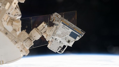 This image shows the Defense Department's experiment pallet, STP-H5, hanging at the end of Canada's robotic arm during installation on the outside of the International Space Station.