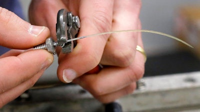 In this Thursday, March 2, 2017, photo, engineer David Wade, hands only, attaches a seal whisker to a clamp in a laboratory at the Naval Undersea Warfare Center, in Newport, R.I. Scientists think real seals, specifically their whiskers, may be the key to a new way for ships and underwater vehicles to sense their environment.