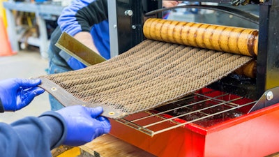 In this December 2016 photo provided by the Argonne National Laboratory, Argonne researchers wring out an 'Oleo Sponge' pad to extract adsorbed crude oil obtained during tests at a seawater tank facility in Leonardo, N.J. Both the oil and the pad can be reused after this process.