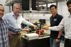 Researchers David Marpaung, Benjamin Eggleton, Yang Liu and Amol Choudhary pointing at a thumbnail-size chip being evaluated in the broadband microwave testbed, inside the Sydney Nanoscience Hub.