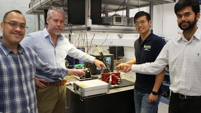 Researchers David Marpaung, Benjamin Eggleton, Yang Liu and Amol Choudhary pointing at a thumbnail-size chip being evaluated in the broadband microwave testbed, inside the Sydney Nanoscience Hub.