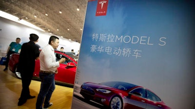 In this April 25, 2016, file photo, visitors look at a Tesla Model S electric car on display at the Beijing International Automotive Exhibition in Beijing. Tesla said August 15, 2016, that the removal of the term autopilot from its website for China was a mistake and the term is being restored.