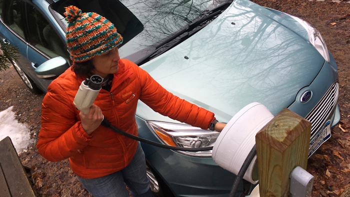 In this Thursday, April 6, 2017 photo, Sunita Halasz shows how she charges her electric car at her home in Saranac Lake, N.Y. Halasz has tips for 'driving electric' along the lonely New York Adirondack Mountains roads: learn where the charging stations are, bring food and books for the kids during three-hour recharges, use the defroster in 10-second bursts since it sucks battery life, and have a backup plan.