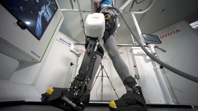 A model demonstrates the Welwalk WW-1000, a wearable robotic leg brace designed to help partially paralyzed people walk at the main system with treadmill and monitor, at Toyota Motor Corp.'s head office in Tokyo, Wednesday, April 12, 2017. Toyota Motor Corp.'s Welwalk WW-1000 system is made up of a motorized mechanical frame that fits on a person’s leg from the knee down.