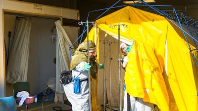 In this Oct. 21, 2016 file photo emergency workers clean various items inside a decontamination tent at Mosaic Life Care, in Atchison, Kan. Federal investigators say Human error and problems with design and labeling led to the release of a large chemical cloud over the city that sent more than 140 people to the hospital last year. The chemical release from MGP Ingredients in Atchison, occurred when a delivery truck driver inadvertently unloaded sulfuric acid into a tank that contained sodium hypochlorite.