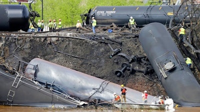 In this May 1, 2014, file photo survey crews in boats look over tanker cars as workers remove damaged tanker cars along the tracks where several CSX tanker cars carrying crude oil derailed and caught fire along the James River near downtown Lynchburg, Va. Inspectors have found almost 24,000 safety defects over a two-year period along United States railroad routes used to ship volatile crude oil. Data obtained by The Associated Press shows many of the defects were similar to problems blamed in past derailments that caused massive fires or oil spills in Oregon, Virginia and Montana.
