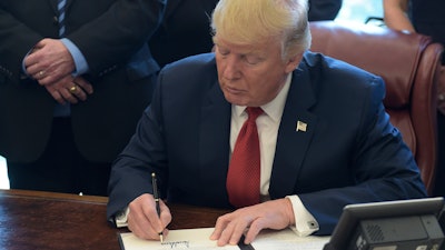 President Donald Trump signs an executive memorandum on investigation of steel imports, Thursday, April 20, 2017, in the Oval Office of the White House in Washington.