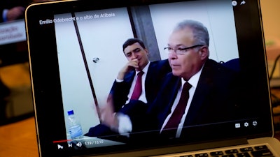 This April 19, 2017 photo shows a computer screen streaming a video of Emilio Odebrecht, right, during his plea bargain deposition, in Rio de Janeiro, Brazil. Often grinning on camera, Odebrecht, former CEO of the Brazilian constructor at the center of the world's biggest corruption scandal, spoke frankly about the hundreds of millions in bribes and illegal financing that his company put into pockets and campaign coffers.