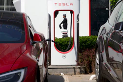 In this Friday, April 14, 2017 photo, a security personnel riding a motorized platform moves past an electric vehicle charging station in Beijing, China. Automakers face a conflict in China's huge but crowded market: Regulators are pushing them to sell electric cars, but buyers want gasoline-hungry SUVs.