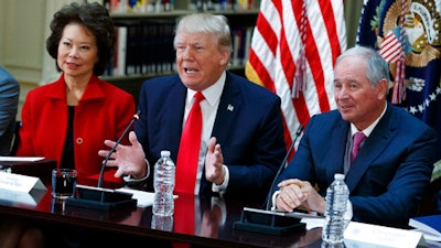 President Donald Trump, flanked by Transportation Secretary Elaine Chao, left, and Blackstone Group CEO Stephen Schwarzman, speaks during a meeting with business leaders in the State Department Library of the Eisenhower Executive Office Building on the White House complex in Washington, Tuesday, April 11, 2017.
